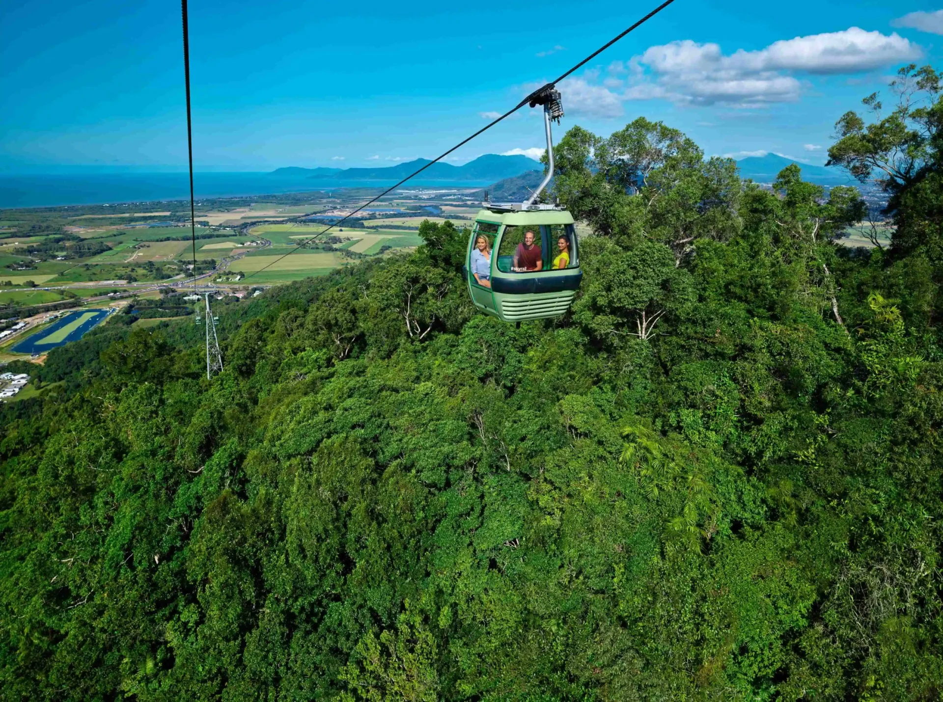 Skyrail gondola above canopy with Coral Coast in background