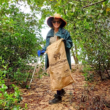 Ranger in full uniform on beach path with large rubbish sack