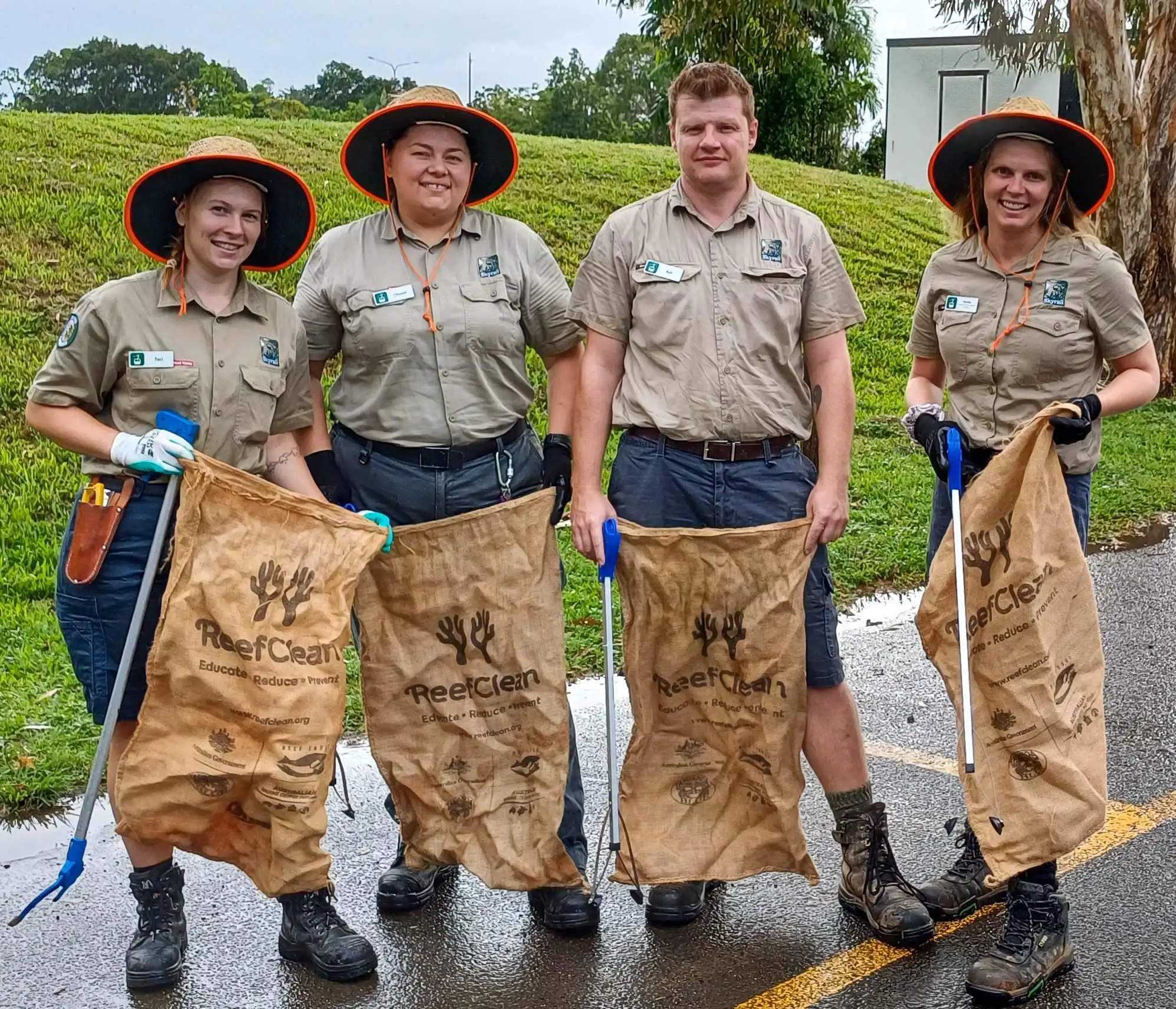 Four Skyrail rangers in full uniform carrying large rubbish sacks and collection tools