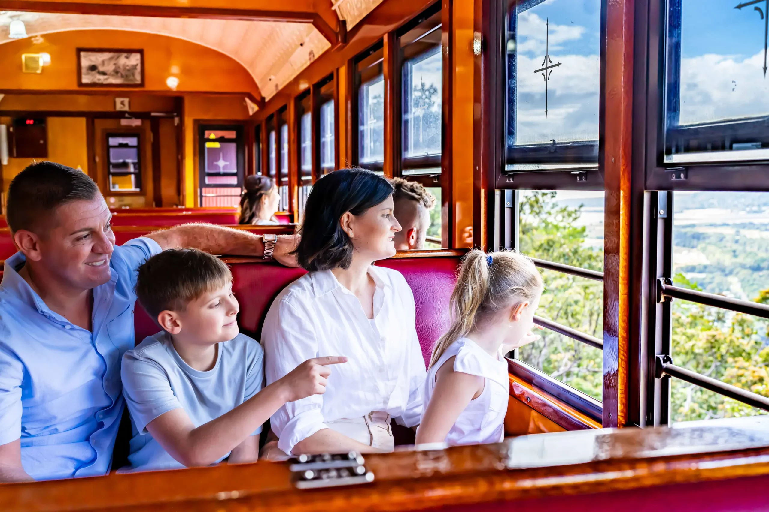 2 adults and two children sit on the train bench seat looking out the window