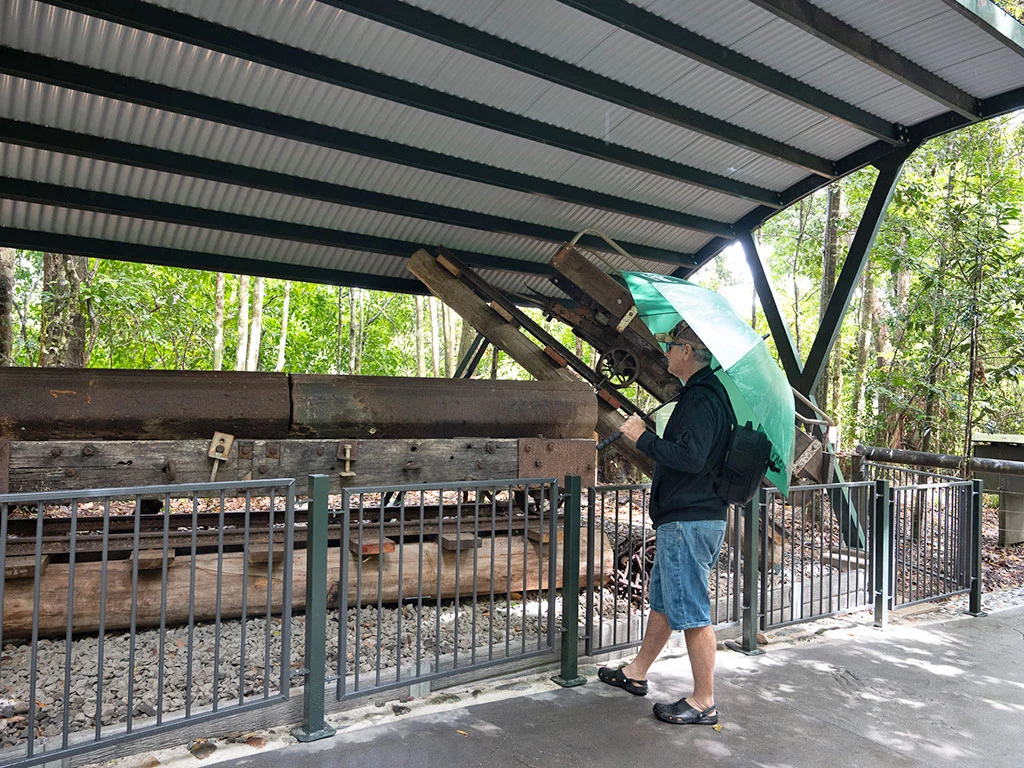 A man stands by himself at the historical precinct, in front of the old haulage trolleys.