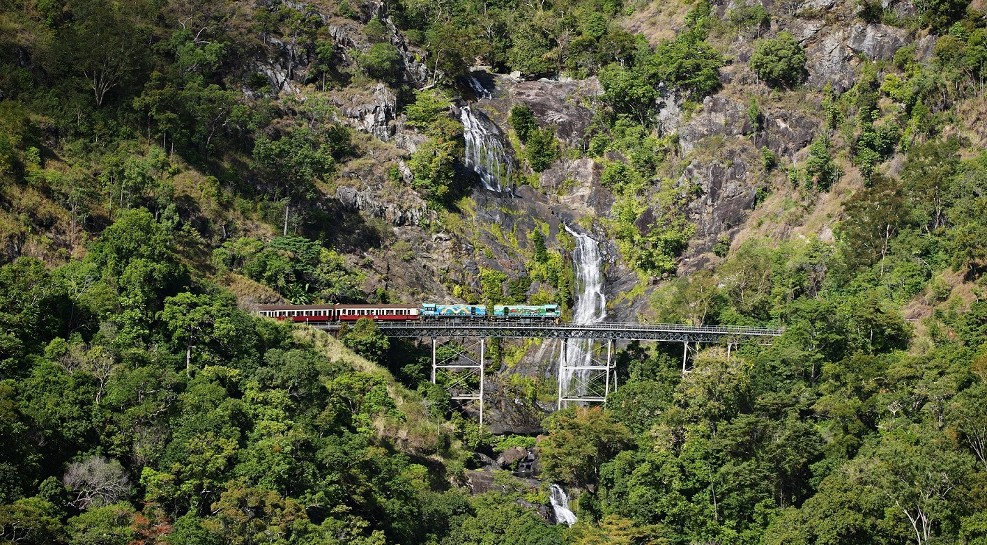 Kuranda scenic railway crossing a large steel bridge in front of stoney creek falls