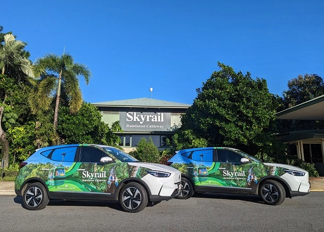 Skyrail electric vehicles parked in front of a building with large sign saying Skyrail Rainforest Cableway