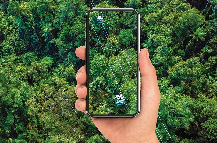a hand holding a phone with skyrail rainforest cableway and rainforest in the background