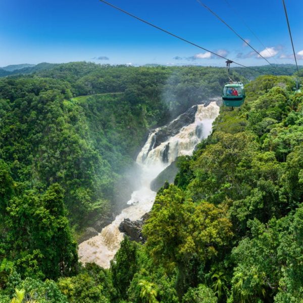 Skyrail gondola hanging high above Barron Falls station with Barron Falls in heavy flood in the background