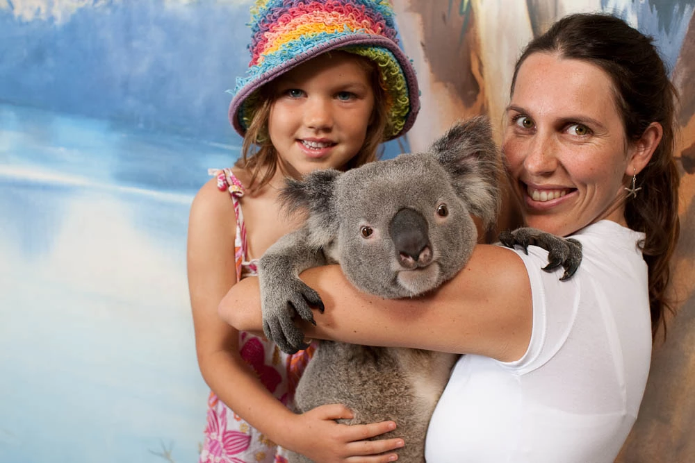 A smiling woman and girl holding a koala